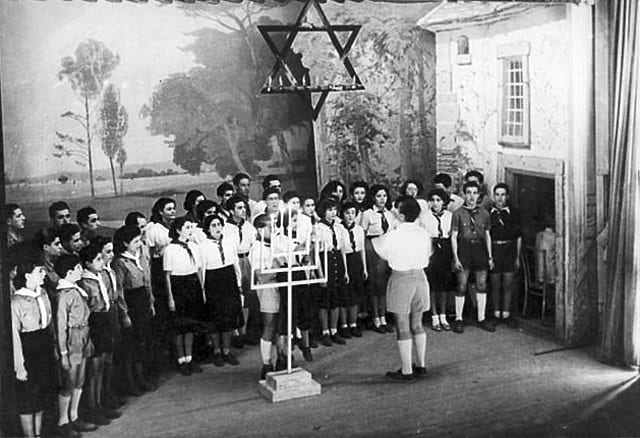 מקהלה של חניכי תנועות הנוער במסיבת חנוכה, תוניס, תוניסיה, 1950 בקירוב (בית התפוצות, המרכז לתיעוד חזותי ע"ש אוסטר, באדיבות דבש רון ואסתר, ישראל)