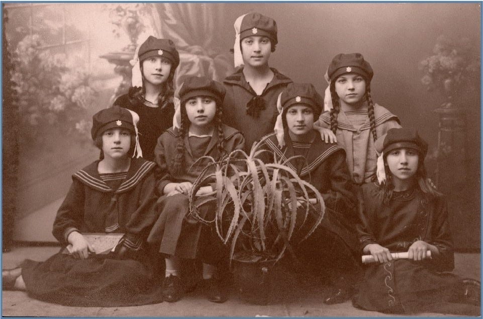 : третий класс школы Тарбут для девочек, Дэвид Городок, Польша, 1924 год. Справа налево: Рэйчел Стаубер, Берача Лутски, Цвия Раппопорт, Юдит Шохат. Нижний ряд справа налево: (?), Ципорин (?), Хайя Фарбер. Центр Остер Визуальной Документации, предоставлено Юдит Шохат.
