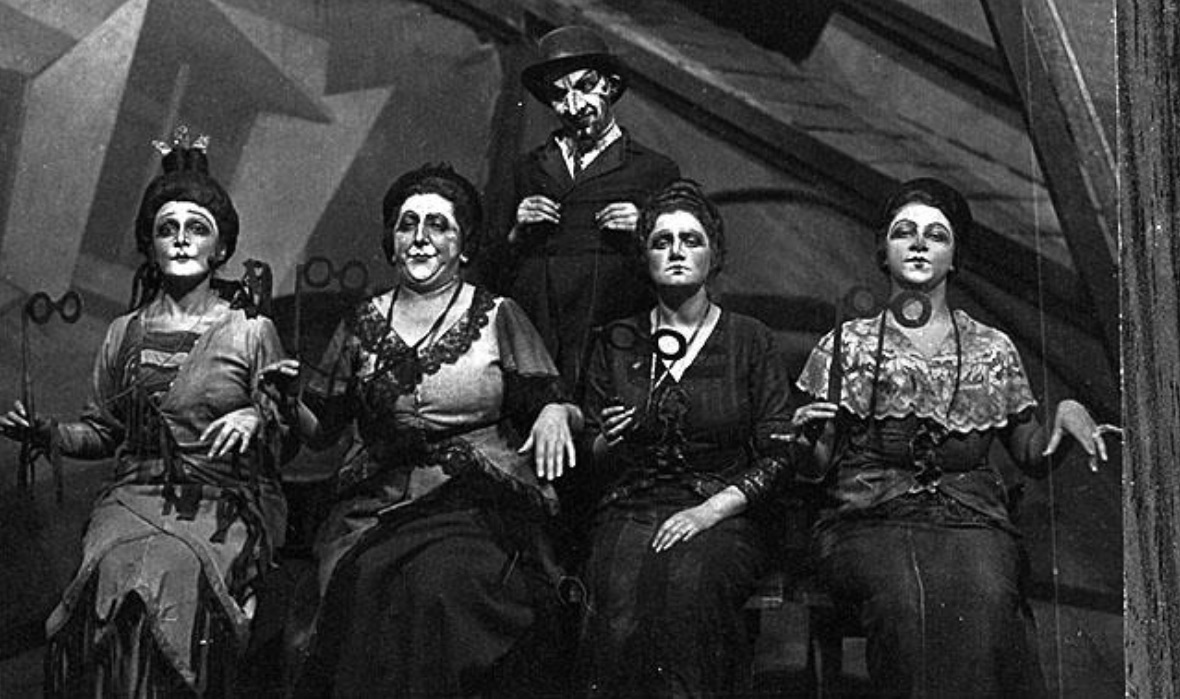 Scene from the play "The Big Win". Moscow, 1923. Their rigid marionette-like sitting positions represented the way of the wealthy in contrast to the Jewish lower classes. (Beit Hatfutsot, the Oster Visual Documentation Center, Zuskin collection)